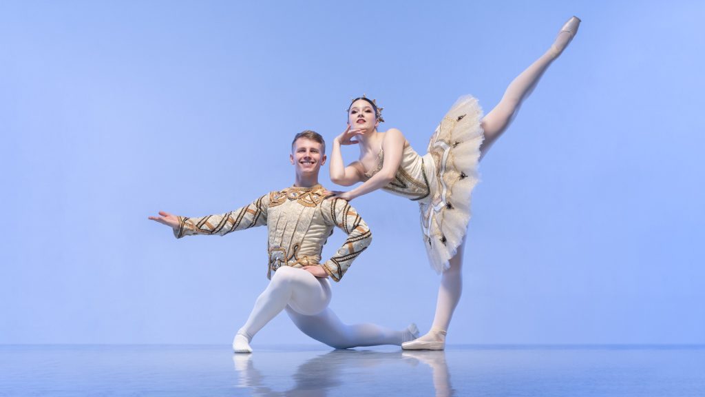 Two ballet dancers pose in costume with a blue background at London Studio Centre